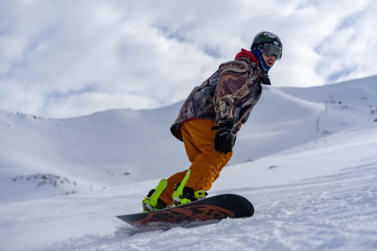 Snowboarder en pendiente nevada con paisaje montañoso