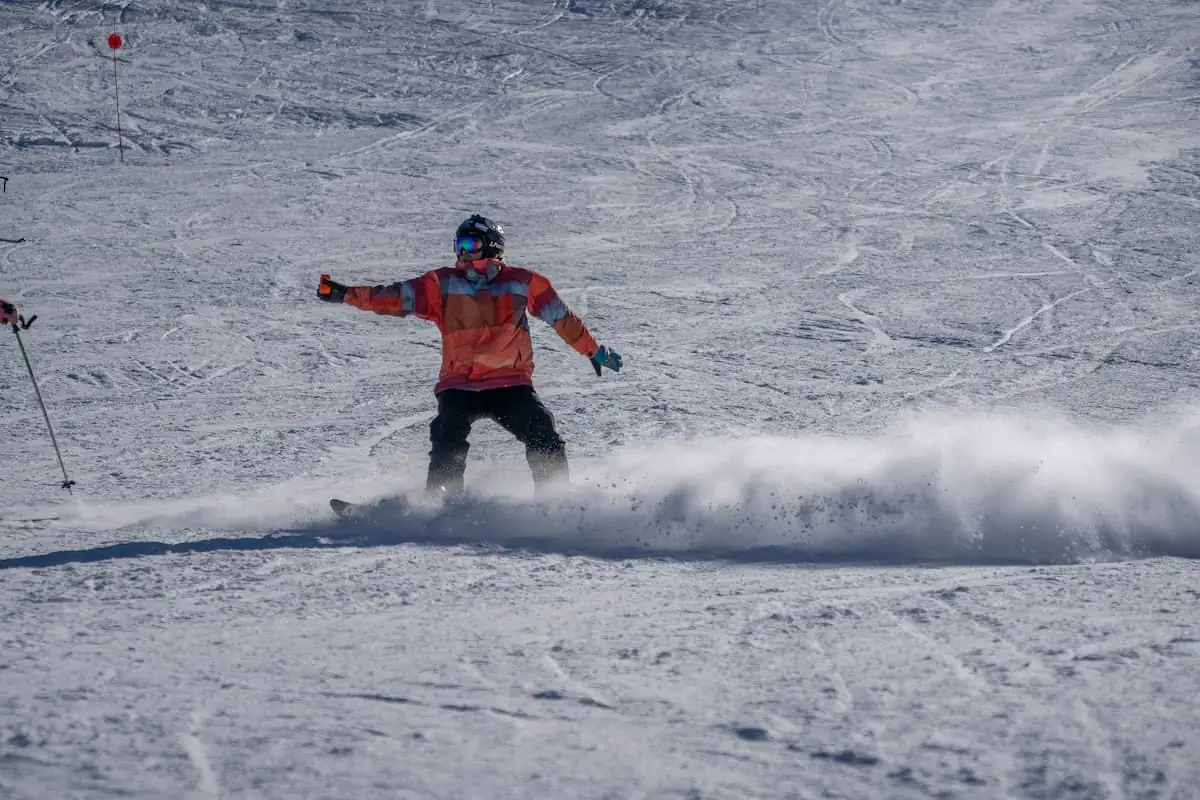 Snowboarder en chaqueta roja saltando en nieve