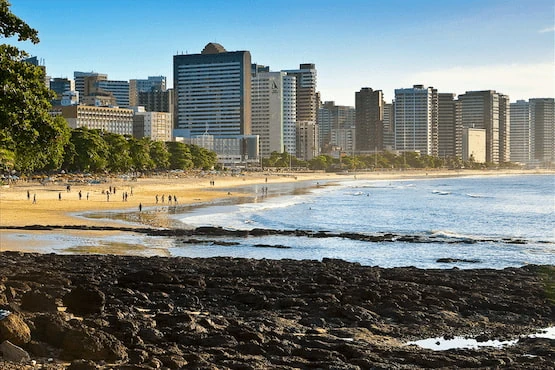 Vista panorámica de una playa urbana con rascacielos al fondo en una ciudad costera de Brasil.