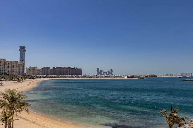 Playa en Dubái con edificios modernos y aguas turquesas del Golfo Pérsico