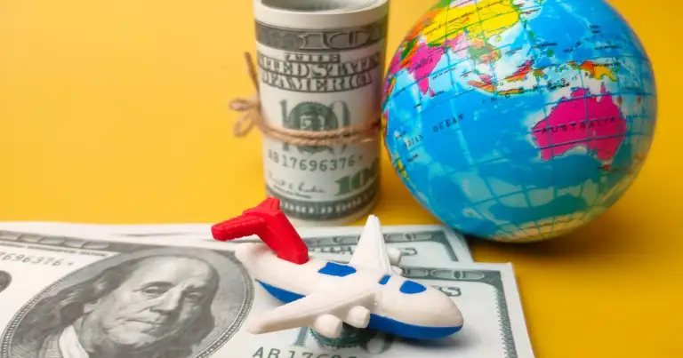 un billete dolar con un avion encima, un mapamundi y un rollo de dolares