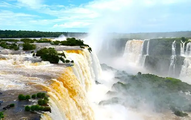 Cascadas masivas con agua amarillenta y blanca, selva verde y rocas