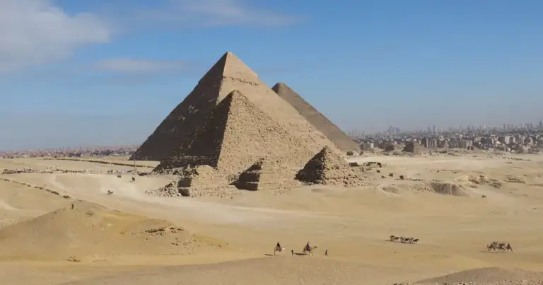 Vista panorámica de las Pirámides de Guiza en Egipto con personas montando camellos