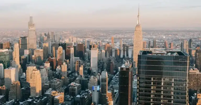 Vista aérea de los rascacielos de Manhattan al atardecer, con el Empire State destacado.