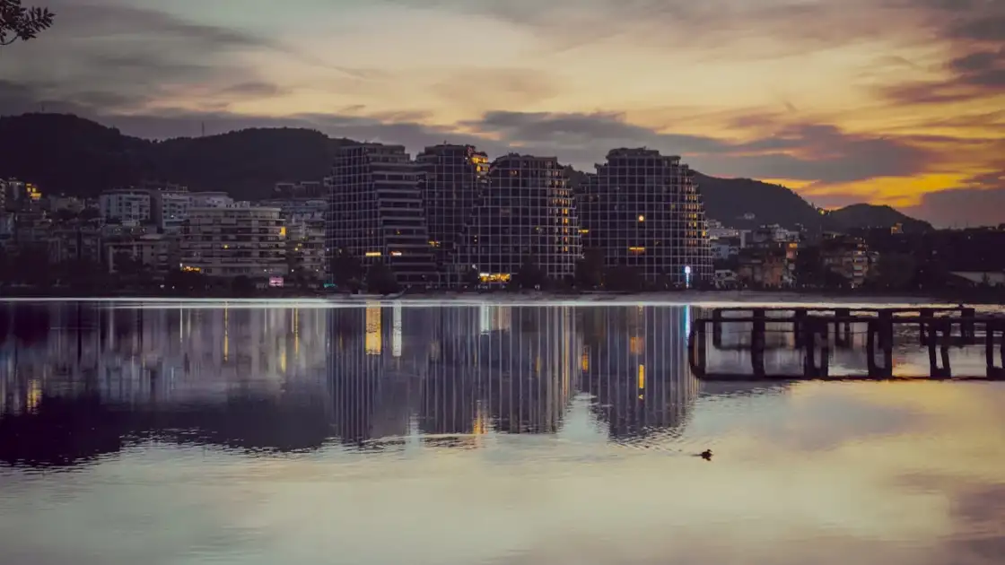 Atardecer en Vlorë, Albania, con edificios modernos reflejados en el mar.
