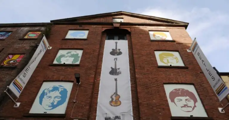 Fachada del Liverpool Beatles Museum con ilustraciones de los cuatro miembros de la banda en colores pop y un cartel vertical con instrumentos musicales.