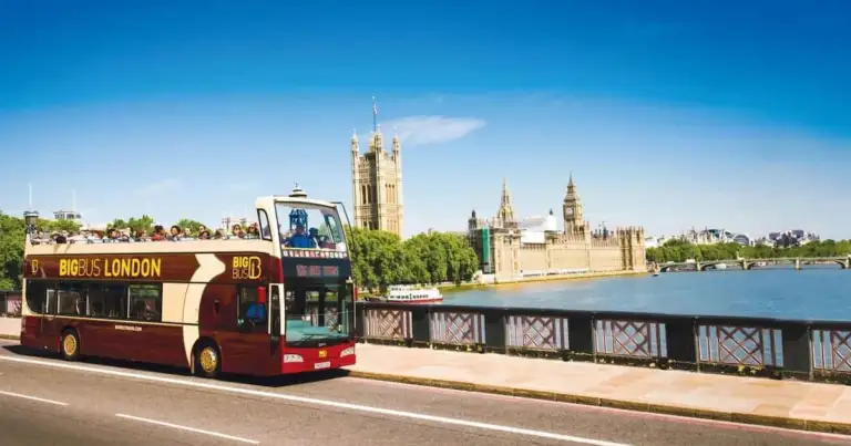 Autobús turístico Big Bus London circulando junto al río Támesis con el Parlamento y el Big Ben de fondo.