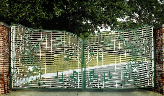 Reja principal de Graceland decorada con notas musicales y figuras de Elvis Presley tocando la guitarra.