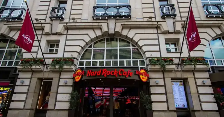 Entrada principal del Hard Rock Cafe en Londres, con sus características banderas burdeos y luces interiores llamativas.
