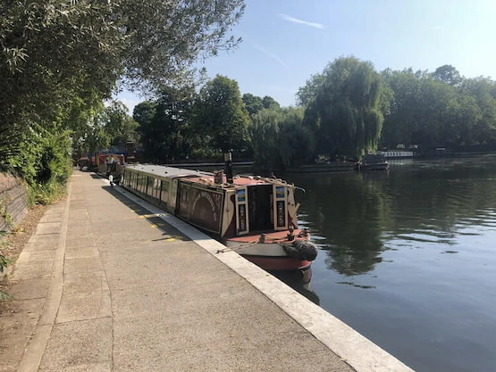 Narrowboat en Little Venice, un paseo diferente para descubrir Londres desde sus canales. Barco estilo narrowboat estacionado en los canales de Londres, rodeado de árboles y vegetación.