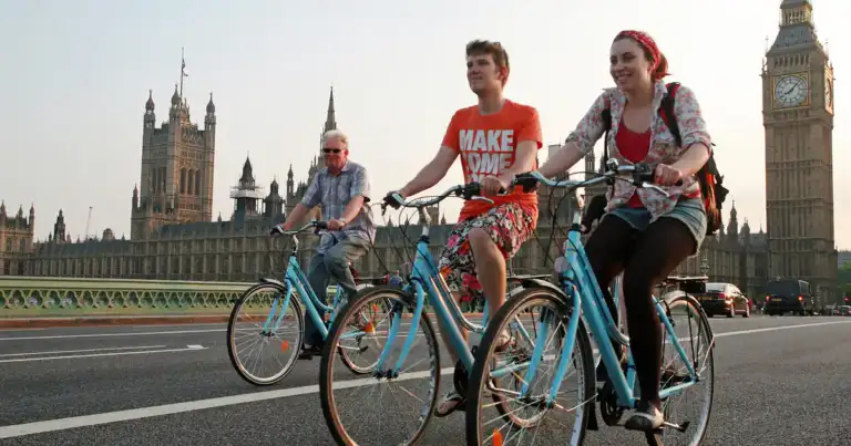 Turistas paseando en bicicleta por Westminster Bridge, con el Big Ben y el Parlamento de fondo en Londres.