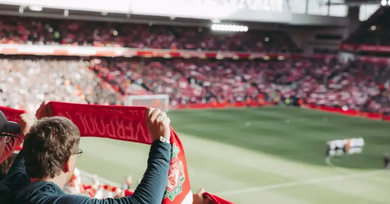 Aficionado del Liverpool levantando su bufanda en Anfield durante un partido.