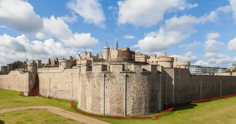 Murallas de la Torre de Londres con cielo azul y nubes, vista panorámica desde el exterior.