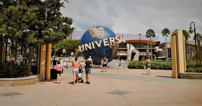 Visitantes caminando hacia el icónico globo de Universal Studios en la entrada principal del parque en Orlando.