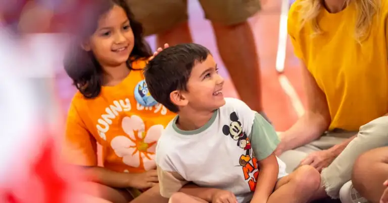 Niños sonrientes participando en una actividad en Disney, acompañados por adultos.