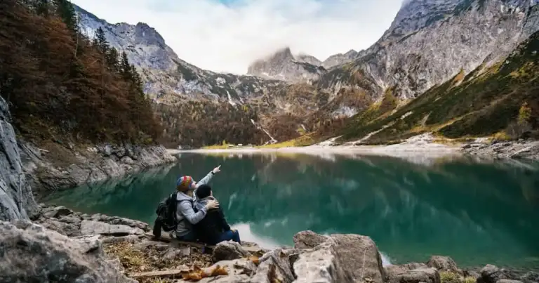 Pareja contemplando un lago entre montañas, disfrutando un viaje planificado con ayuda de la inteligencia artificial para optimizar gastos y experiencias.