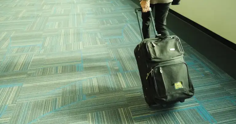 Persona caminando por el aeropuerto con una maleta de mano, representando los nuevos límites de tamaño permitidos por las aerolíneas.