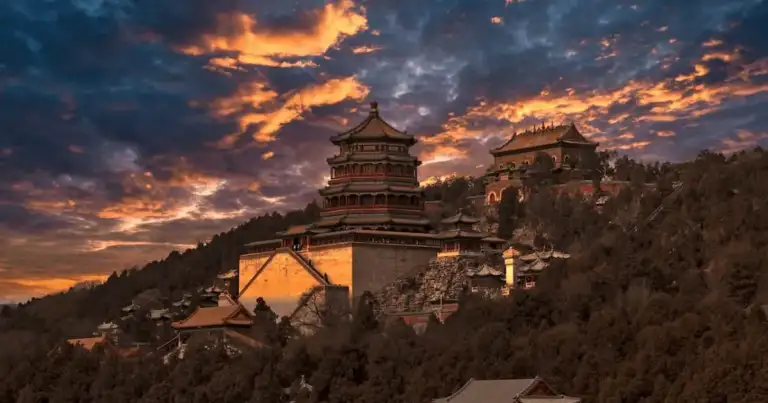 Templo antiguo en China iluminado por el atardecer, rodeado de montañas y arquitectura tradicional.