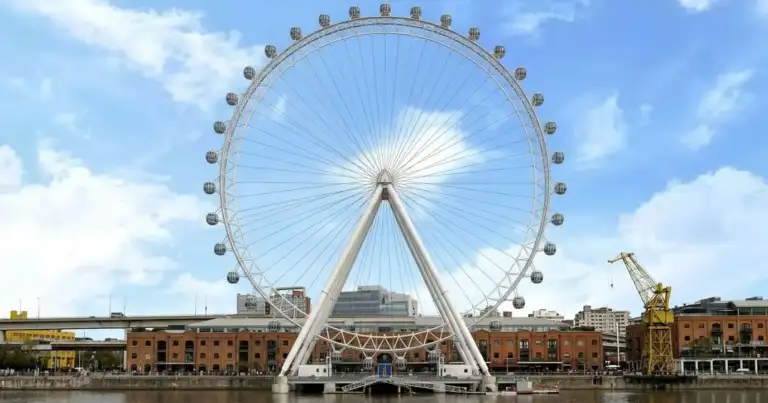 Rueda gigante tipo London Eye junto al río en entorno urbano