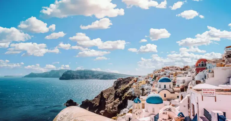 Vista del pueblo de Oia en Santorini con casas blancas y cúpulas azules frente al mar Egeo