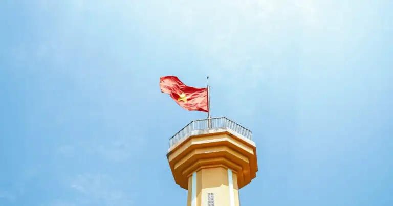 Bandera de Vietnam ondeando en torre mirador bajo cielo despejado.