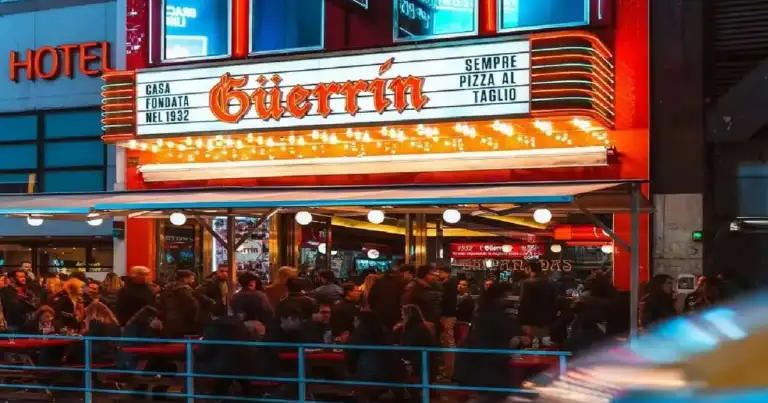Pizzería Guerrin de noche en Buenos Aires con gran cantidad de gente y su clásica fachada iluminada