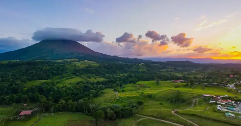 Volcán y paisaje verde de Costa Rica al atardecer, ideal para viajar en temporada seca o de naturaleza.