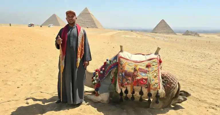 Guía local y camello frente a las pirámides en Egipto