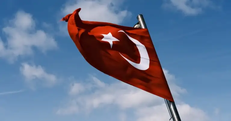 Bandera de Turquía ondeando al viento sobre fondo de cielo azul.