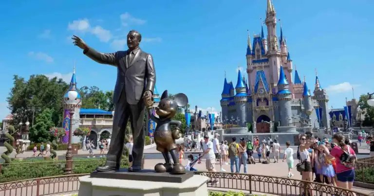 Castillo de Cenicienta en Magic Kingdom con visitantes frente a la estatua de Walt Disney y Mickey Mouse en Walt Disney World.