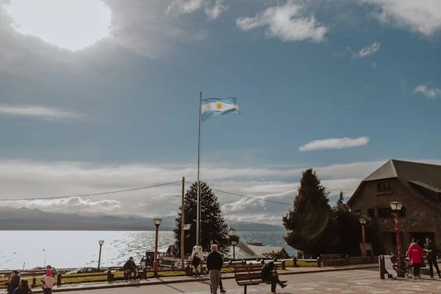 Destinos nacionales en el Hot Sale de viajes Bandera argentina frente a un paisaje de lago y montaña, como referencia a destinos nacionales con promociones durante el Hot Sale de viajes.