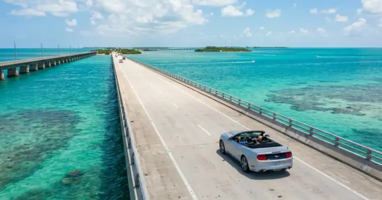 Auto recorriendo un puente sobre aguas turquesas en la ruta de Miami a Key West, una imagen que muestra el viaje por la Overseas Highway y la distancia entre ambos destinos de Florida.