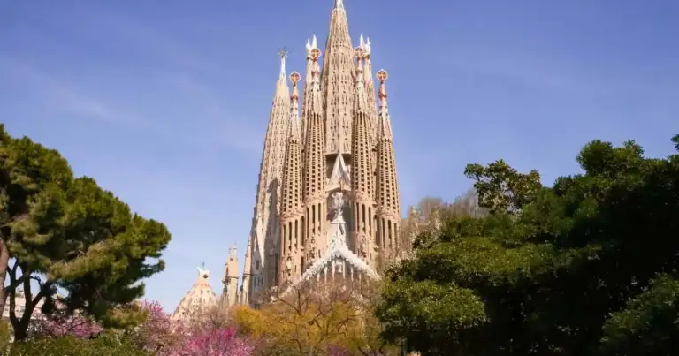 Vista de la Sagrada Familia en Barcelona rodeada de árboles, una de las visitas principales para calcular el presupuesto del viaje.