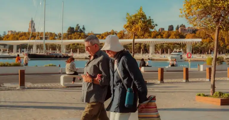 Pareja de adultos mayores caminando por un paseo costero, imagen asociada a destinos accesibles para jubilados en 2026.