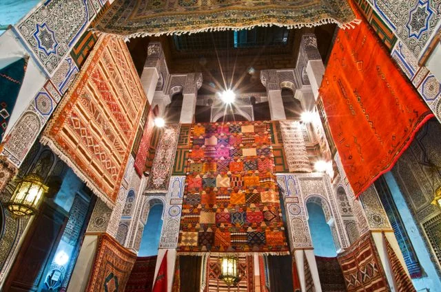 Interior tradicional en Marruecos con alfombras, azulejos y arquitectura decorada, imagen relacionada con qué ver en el país.