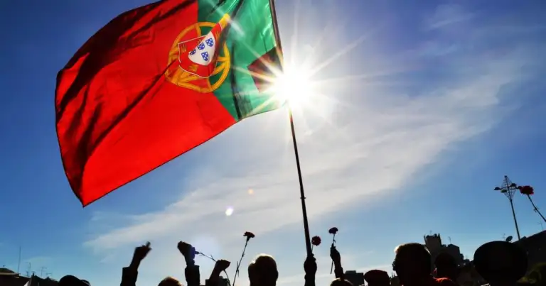 Bandera de Portugal ondeando al sol, imagen relacionada con una guía sobre dónde queda Portugal y qué saber antes de viajar.