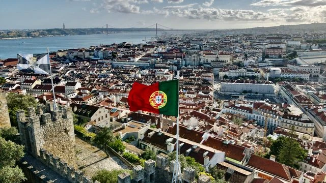 Vista panorámica de Lisboa, capital de Portugal, con la bandera portuguesa y el río Tajo al fondo.
