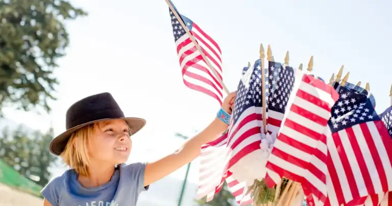 Niño con pequeñas banderas de Estados Unidos durante una celebración del Fourth of July, imagen relacionada con dónde vivir el Día de la Independencia.