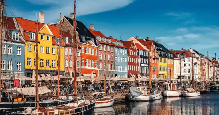 Canal de Nyhavn en Copenhague con casas de colores, barcos y terrazas, una imagen asociada a calidad de vida urbana.