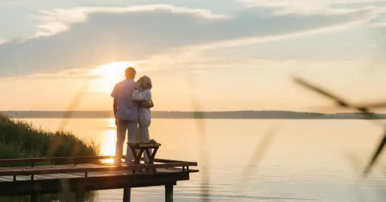 Pareja de adultos mayores contemplando un lago al atardecer, imagen relacionada con paquetes de viajes para jubilados en 2026.