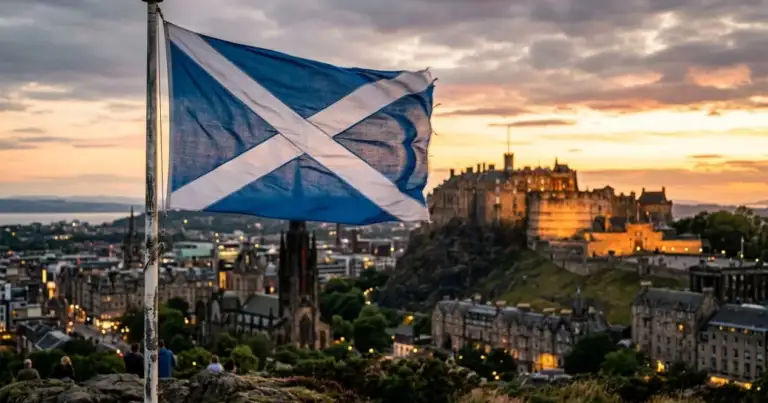 Bandera de Escocia con el castillo de Edimburgo al fondo, imagen de la capital escocesa al atardecer.