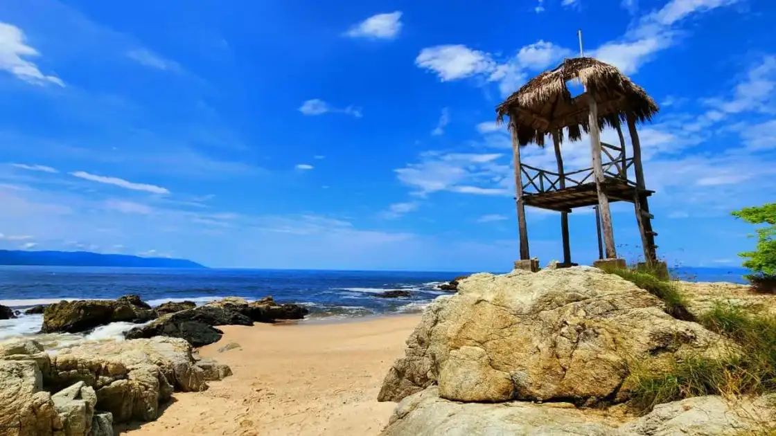 Playa rocosa cerca de Puerto Vallarta con palapa de madera frente al océano Pacífico mexicano.