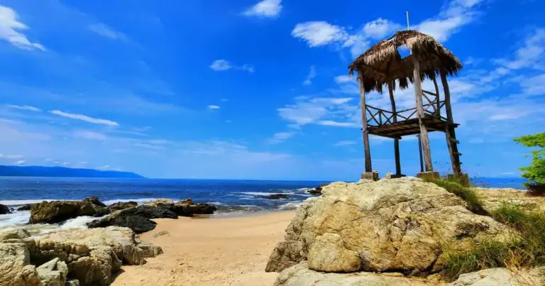 Playa rocosa cerca de Puerto Vallarta con palapa de madera frente al océano Pacífico mexicano.