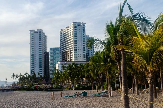 Playa de Puerto Vallarta con palmeras, hoteles frente al mar y arena clara en la costa del Pacífico mexicano.