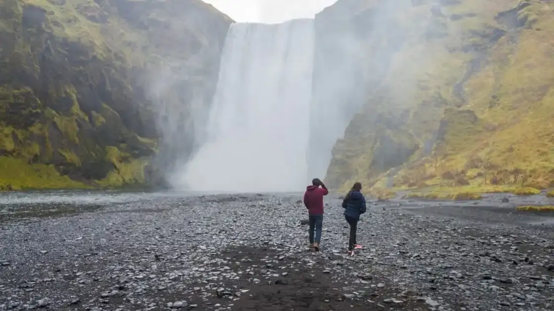 Viajeros frente a la cascada Skógafoss, una de las más famosas del sur de Islandia.
