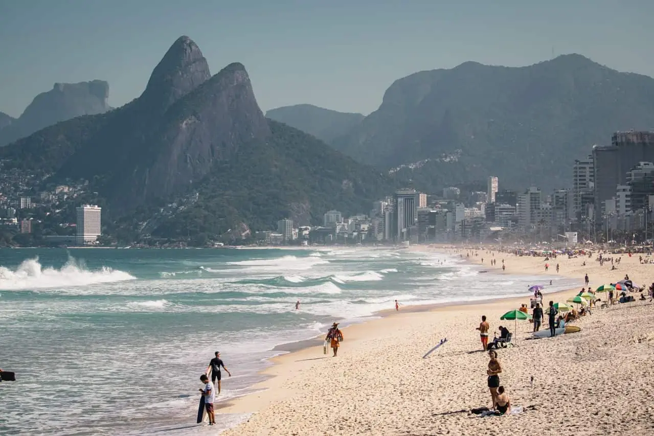 Playa de Ipanema en Río de Janeiro con familias y bañistas, y el Morro Dois Irmãos al fondo.