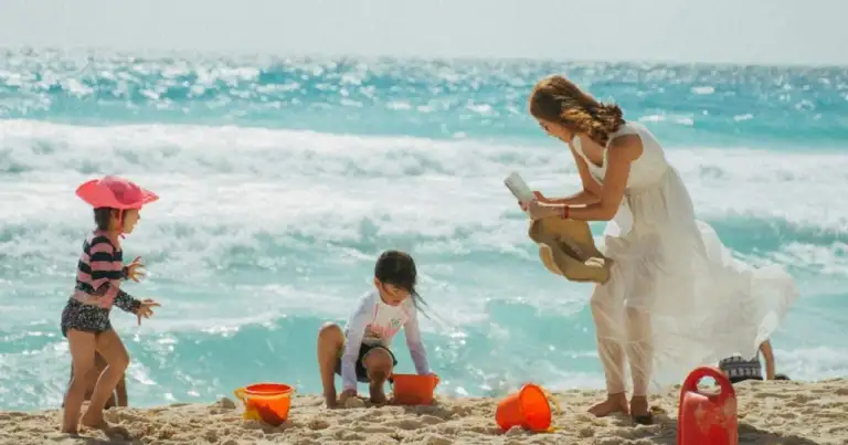 Madre con niños jugando en la arena frente al mar durante unas vacaciones familiares en una playa de México.