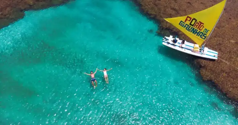 Vista aérea de una piscina natural en Porto de Galinhas, Pernambuco, con aguas turquesas y una jangada tradicional.