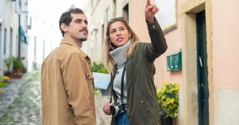 Dos turistas conversan y señalan un lugar mientras recorren una calle de una ciudad extranjera.