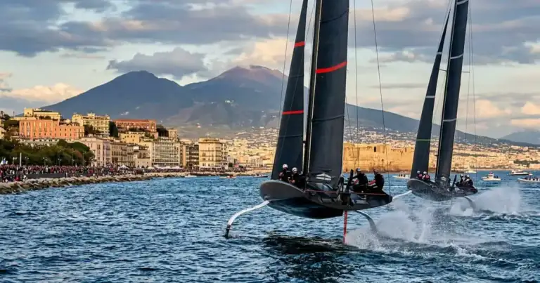 Veleros de competición navegan frente a Nápoles con el Vesubio al fondo, escenario de la America’s Cup 2027